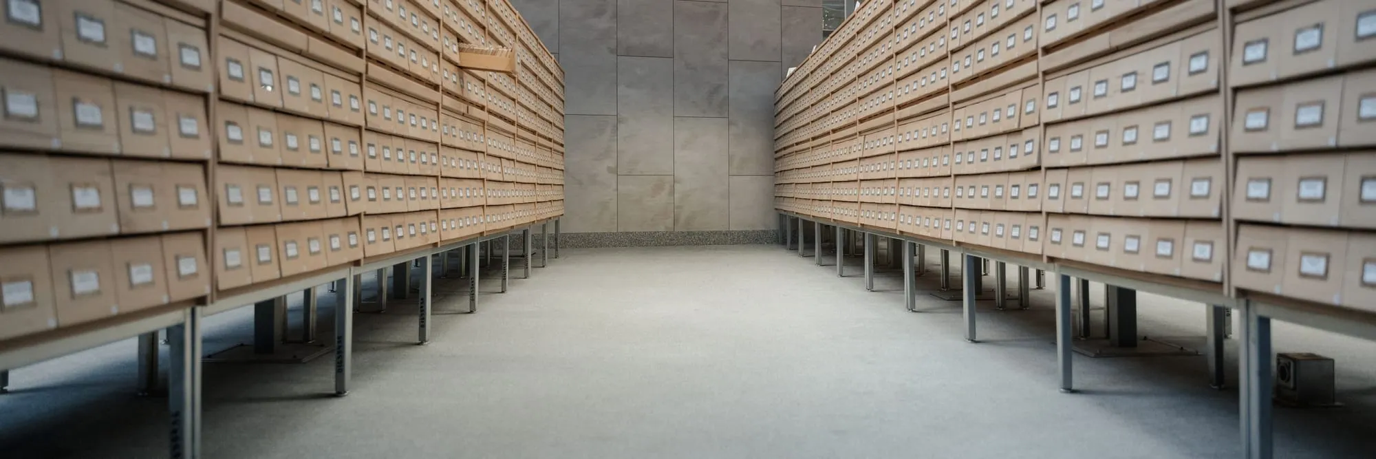 A long corridor between two banks of card-index drawers, every drawer labelled, receding to the far wall.